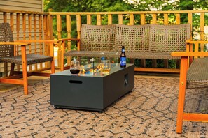Un patio amueblado con una mesa baja moderna, sillas de mimbre y un banco de madera.