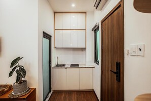 Una cocina compacta con armarios blancos, una puerta de madera y un lavamanos pequeño.