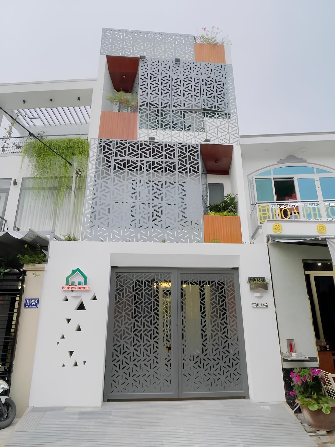 A modern building with a geometric facade, a large entrance gate, and a sign indicating a hotel.