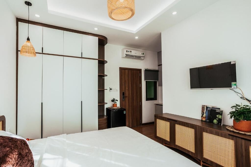 A modern bedroom with a bed, a TV, a wardrobe, and a small desk area.