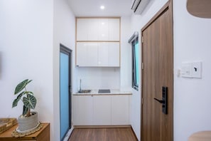 Una cocina compacta con armarios blancos, un lavamanos y una puerta de madera.