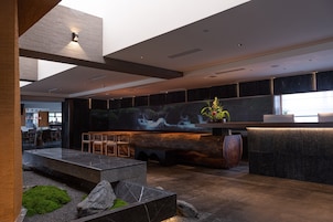 A modern lobby with a reception desk, seating area, and a large wall-mounted screen.