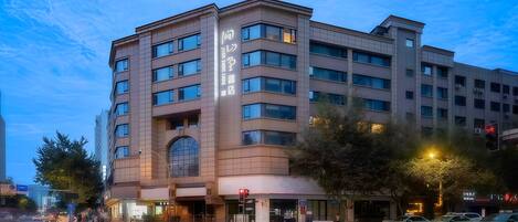 A multi-story hotel with a prominent entrance, large windows, and a clear sky.