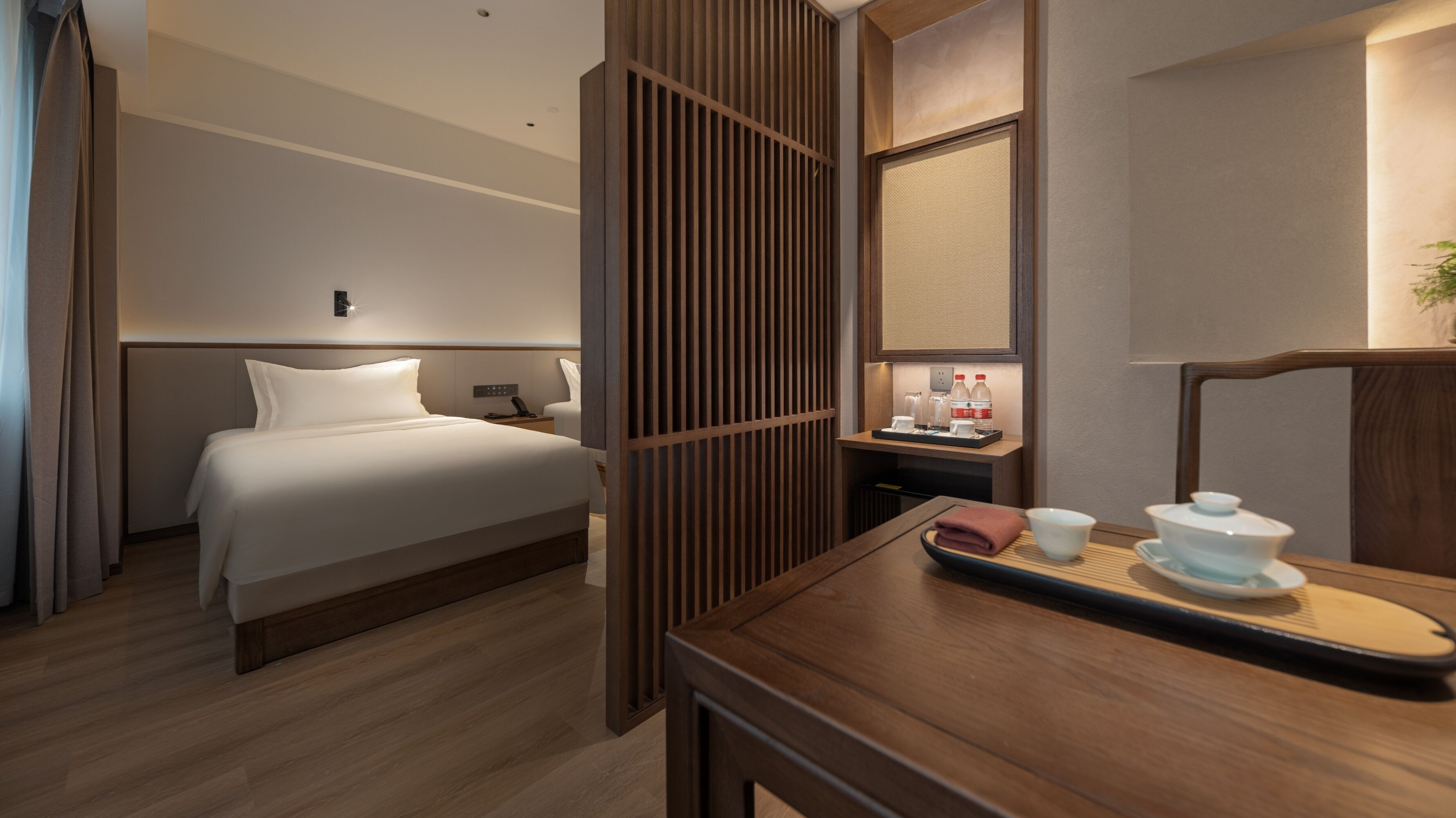 Habitación de hotel con cama, mesita de noche y un separador de madera.