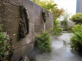 Fachada moderna de edificio con superficie texturizada y fuente de agua.
