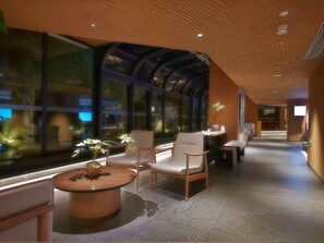 A modern interior with a curved ceiling, large windows, and a seating area with a round table and chairs. - Chengdu Jian Shan Hall Hotel (Chengdu)