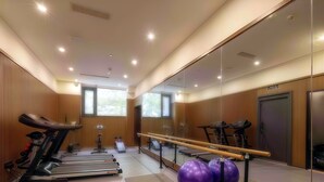 Un gimnasio moderno con cintas de correr, elípticas, una barra para ejercicios y pelotas de ejercicio grandes.