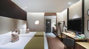 A hotel room with two beds, a desk, a television, and a chair.