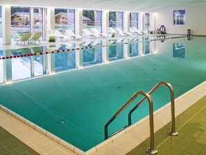 An indoor swimming pool with clear water, a diving board, and lounge chairs along the side. - Gemütliche Unterkunft ohne Luxus by Interhome (Zinal)