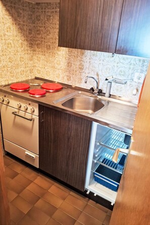 A kitchen with a built-in oven, a sink, and a refrigerator. - Gemütliche Unterkunft ohne Luxus by Interhome (Zinal)