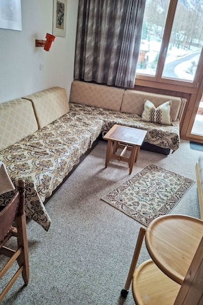 Ein Wohnzimmer mit einer Sofagarnitur, einem kleinen Holztisch und einem gemusterten Teppich.
