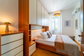 Ein Schlafzimmer mit Bett, Nachttischen, einer Lampe, einem Kleiderschrank und einem Fenster mit Vorhängen.