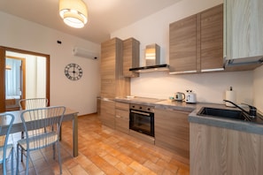 Eine moderne Küche mit Holzausstattung, einem Einbauofen und einem Essbereich mit Tisch und Stühlen.