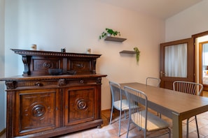 A dining area with a wooden table and chairs, a cabinet with decorative carvings, and a door leading to another room. - Manzoni 2 - Beyond the Duomo (Como)
