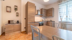 A modern kitchen with wooden cabinets, a dining table, and chairs. - Manzoni 2 - Beyond the Duomo (Como)