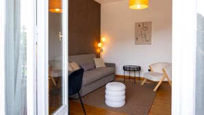 A modern living room with a sofa, a round ottoman, a chair, a small table, and a wall-mounted lamp. - Manzoni 2 - Beyond the Duomo (Como)