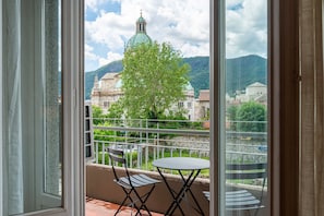 A balcony with a table and chairs, a view of a building with a dome, and a tree. - Manzoni 2 - Beyond the Duomo (Como)