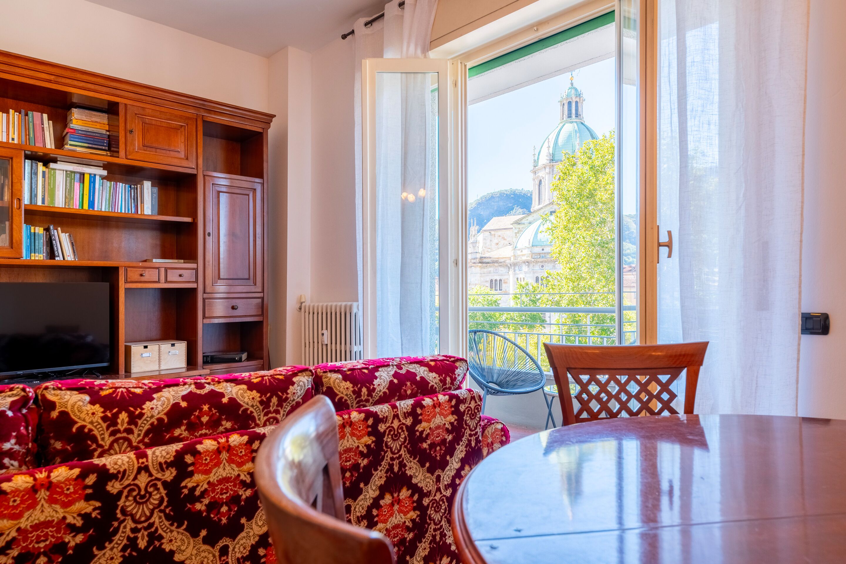 Un salon avec un canapé, des fauteuils, un téléviseur et une bibliothèque.