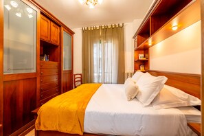 Ein Hotelzimmer mit Bett, Holzschrank und einem Vorhangfenster.