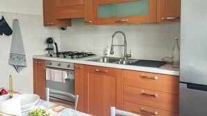 A kitchen with wooden cabinets, a gas stove, a sink, and a refrigerator. - Gorgeous apartment in Marotta with WiFi (Marotta)