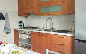 Eine Küche mit Holzausstattung, einem Gasherd, einer Spüle und einem Kühlschrank.