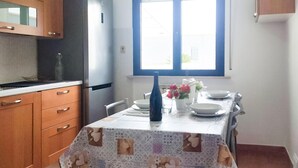 A kitchen with wooden cabinets, a refrigerator, a dining table with a patterned tablecloth, and a window above the table. - Gorgeous apartment in Marotta with WiFi (Marotta)