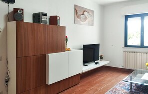 A modern living room with a TV, wooden cabinet, and artwork on the wall.
