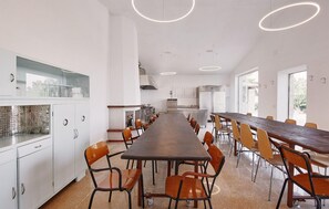 A modern kitchen with a long dining table and chairs, white cabinetry, and a view of the outdoors. - Lovely home in San Severino Marche (San Severino Marche)