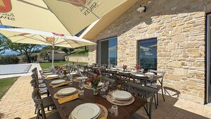 Un área de comedor al aire libre con muros de piedra, sombrillas grandes y mesas dispuestas para una comida.