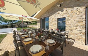 An outdoor dining area with stone walls, large umbrellas, and tables set for a meal. - Lovely home in San Severino Marche (San Severino Marche)