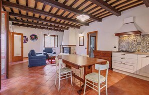 A spacious living area with a wooden dining table, two chairs, a sofa, and a fireplace. - Beautiful home in San Severino Marche with outdoor swimming pool (San Severino Marche)
