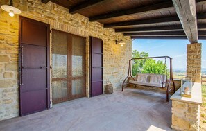 A stone-walled room with a swing seat and a view of greenery. - Beautiful home in San Severino Marche with outdoor swimming pool (San Severino Marche)