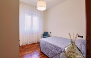 A bedroom with a bed, a chair, a window with curtains, and a vase with reed sticks. - Lovely home in San Severino Marche (San Severino Marche)