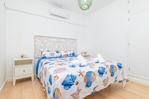 A bedroom with a bed, nightstands, a wall-mounted air conditioner, and a decorative ceiling light fixture. - CAN PARÍS – Beautiful house just two minutes from the beach with free Wi-Fi (Santa Margalida)