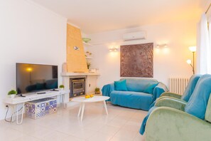 Ein modernes Wohnzimmer mit Flachbildfernseher, Kamin, blauem Sofa und einer dekorativen Wandarbeit.
