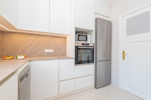 Eine moderne Küche mit weißen Schränken, einem eingebauten Ofen, einer Mikrowelle und einem Kühlschrank.