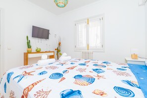 A hotel room with a bed, a TV, a window, and a bedside table. - CAN PARÍS – Beautiful house just two minutes from the beach with free Wi-Fi (Santa Margalida)