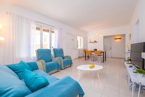A modern living room with a sofa set, a dining area with chairs and a table, and a television on a stand. - CAN PARÍS – Beautiful house just two minutes from the beach with free Wi-Fi (Santa Margalida)