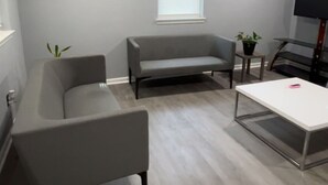 Ein modernes Wohnzimmer mit einem grauen Sofa, einem kleinen Tisch und einem Fernseher.