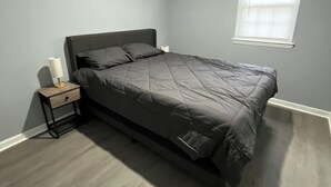 A bedroom with a bed, a nightstand, a window, and a ceiling light.
