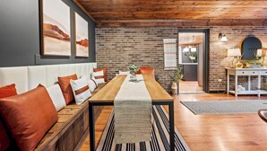 A dining area with a wooden table, bench seating, and a brick wall. - 3 King Suites, Game Room, Hot Tub - 2 Mi to Island (Pigeon Forge)