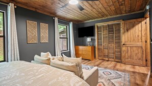 A bedroom with a bed, a dresser, a television, and a wardrobe. - 3 King Suites, Game Room, Hot Tub - 2 Mi to Island (Pigeon Forge)