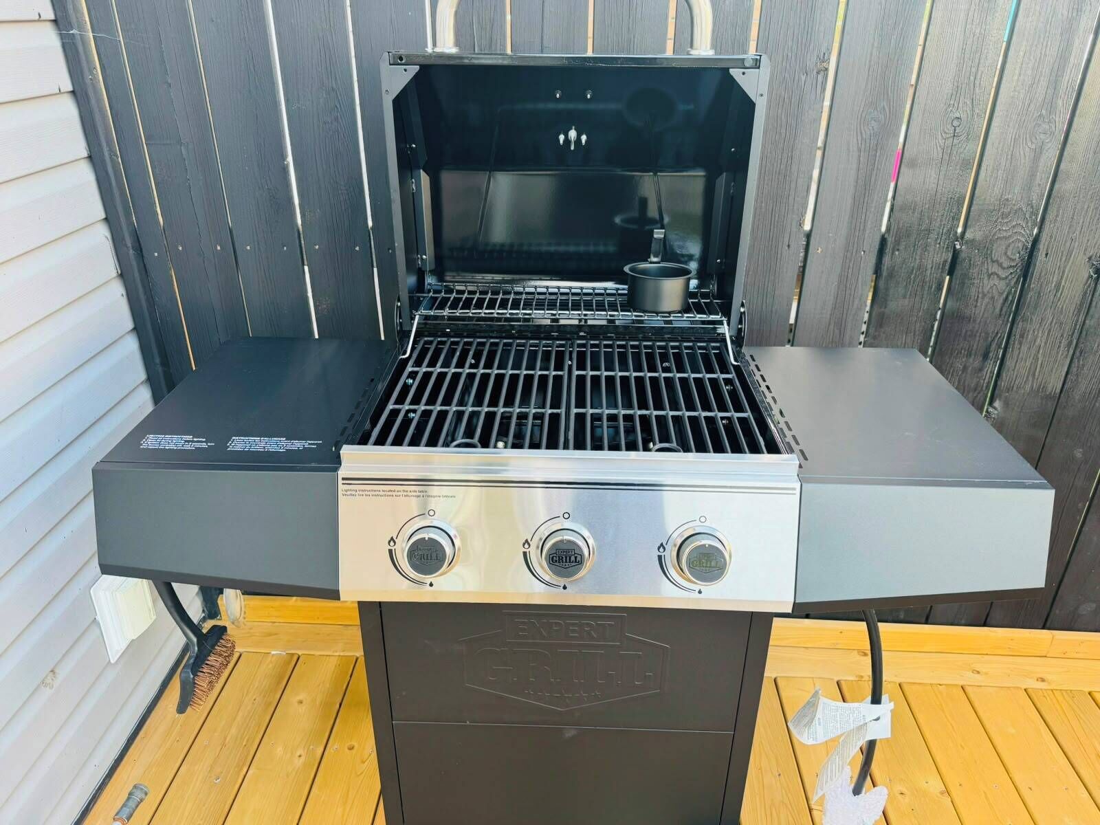 Ein tragbarer Grill mit drei Kochfeldern, einer Bedienkonsole und einem Grillrost.