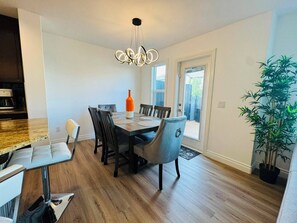 Un coin repas avec une table en bois, des chaises, un luminaire suspendu moderne et une plante en pot.