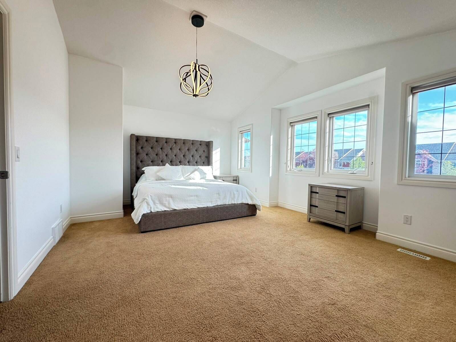 Een slaapkamer met een groot bed, een dressoir en een plafondlamp.