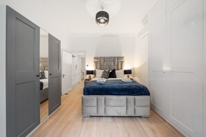 A bedroom with a bed, bedside tables, a wardrobe, and a mirror. - Superior Bedroom Apartment In Mayfair (London)