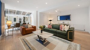 A modern living room with a sofa, a coffee table, and a lamp. - Superior Bedroom Apartment In Mayfair (London)