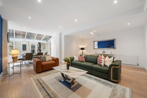 A modern living room with a sofa, a coffee table, and a lamp. - Superior Bedroom Apartment In Mayfair (London)