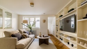 Ein modernes Wohnzimmer mit Sofa, Couchtisch, Fernseher und Einbauschränken.