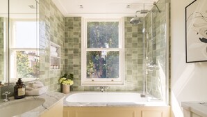 Ein Badezimmer mit großem Fenster, einer Badewanne und einer Dusche.